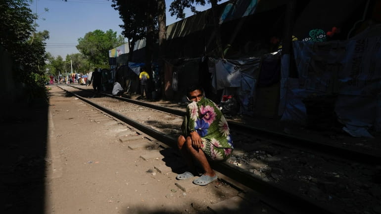 A migrant from Maracaibo, Venezuela, sits on a railroad track...